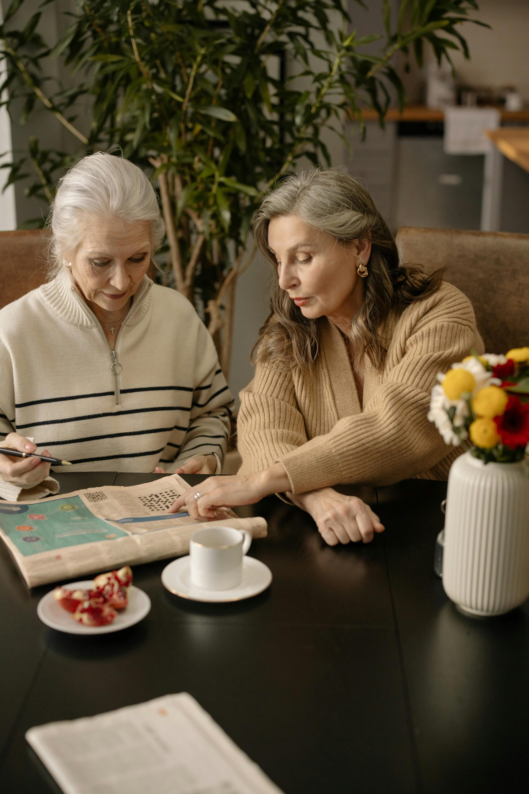 Elderly women solving a crossword puzzle, fostering friendship and mental stimulation indoors.